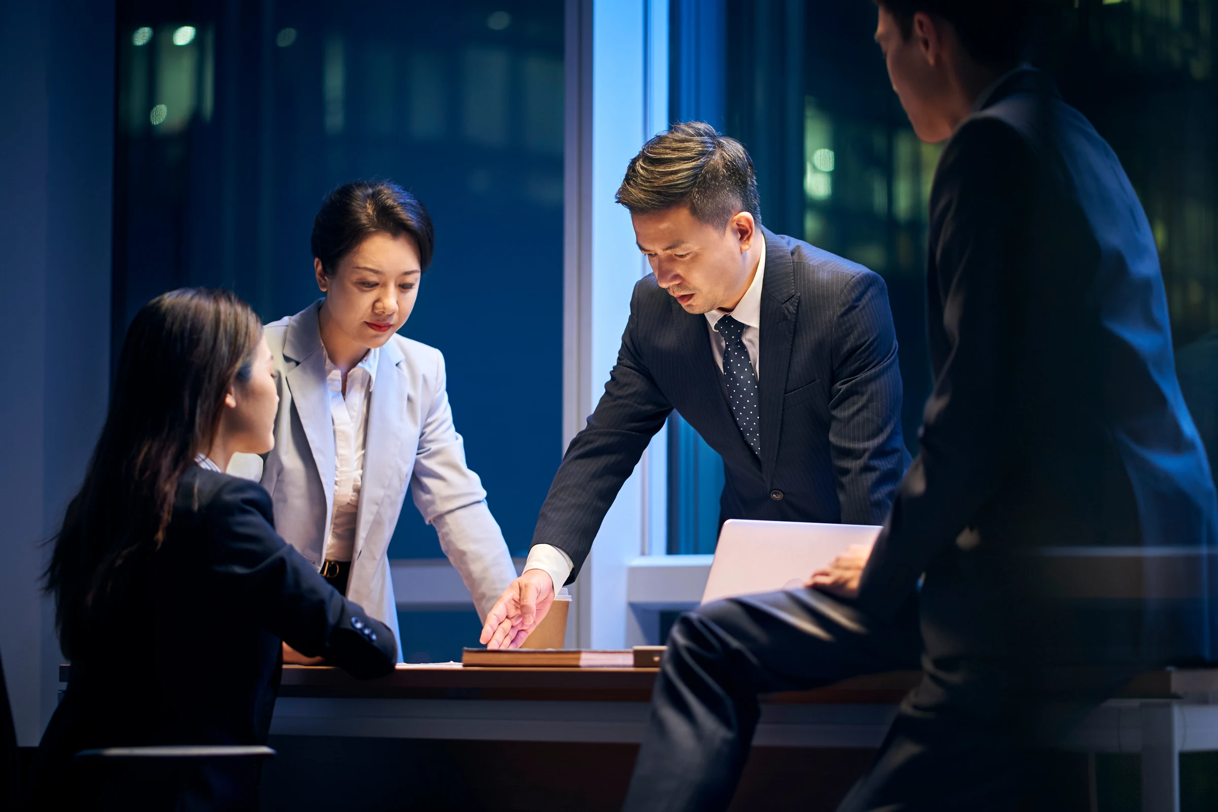 夜の会議室で対応方針を話し合うチームのイメージ写真