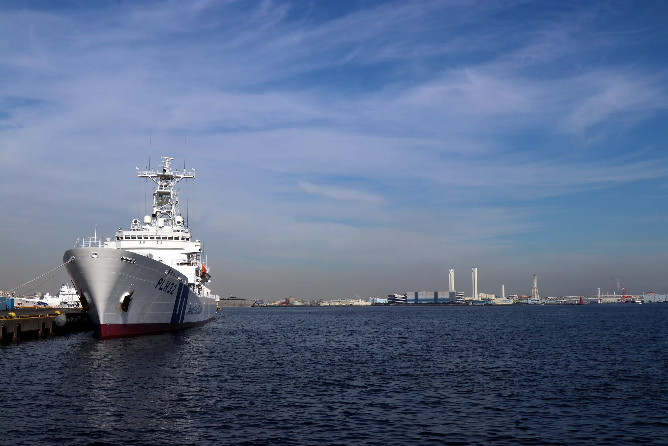 A vessel in a harbor with the opposite shore visible